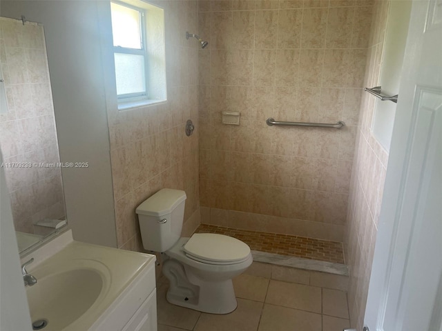 bathroom with vanity, toilet, tile patterned floors, tile walls, and tiled shower