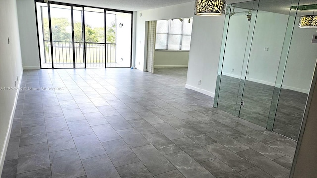 unfurnished room with baseboards and expansive windows