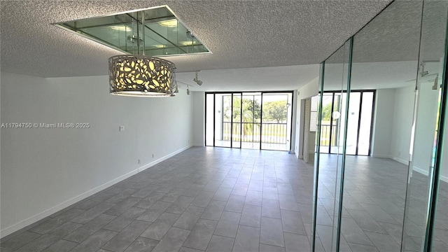 unfurnished room featuring a textured ceiling and baseboards
