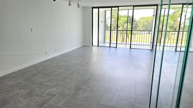 spare room featuring expansive windows, baseboards, and a wealth of natural light