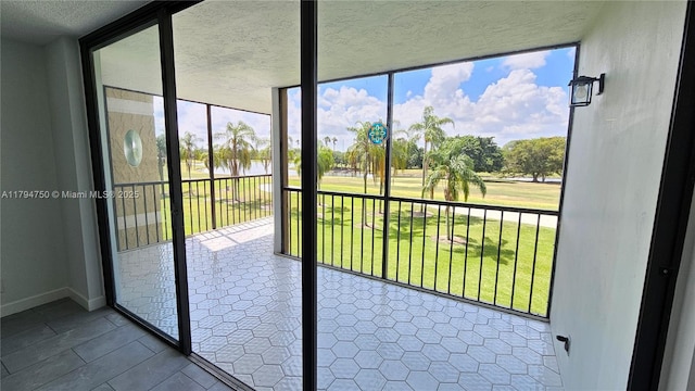 doorway to outside featuring a water view, a textured ceiling, plenty of natural light, and expansive windows