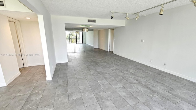 unfurnished room with track lighting, a textured ceiling, and visible vents