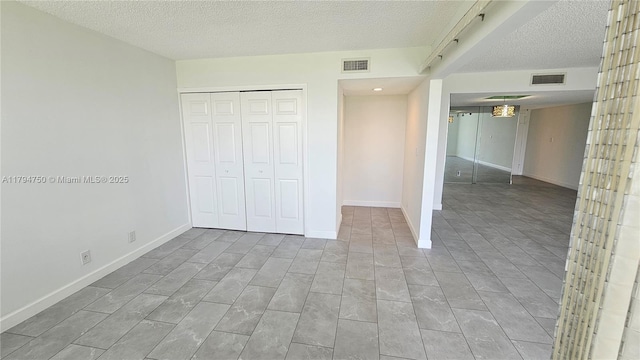 unfurnished bedroom with a textured ceiling, visible vents, and a closet