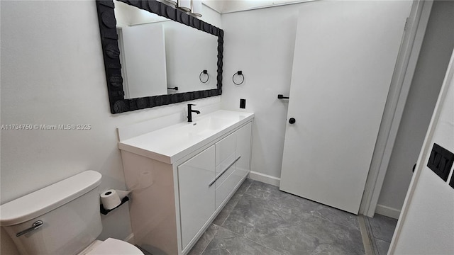bathroom featuring toilet, baseboards, and vanity