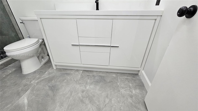 bathroom featuring vanity, baseboards, toilet, and marble finish floor