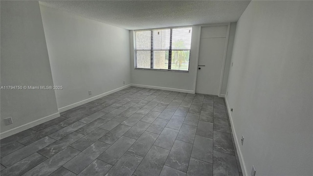 unfurnished room with baseboards and a textured ceiling