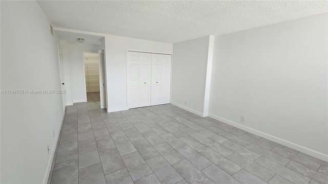 unfurnished bedroom with a closet, a textured ceiling, and baseboards