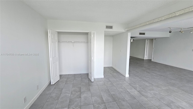 unfurnished bedroom featuring visible vents, a textured ceiling, baseboards, and a closet
