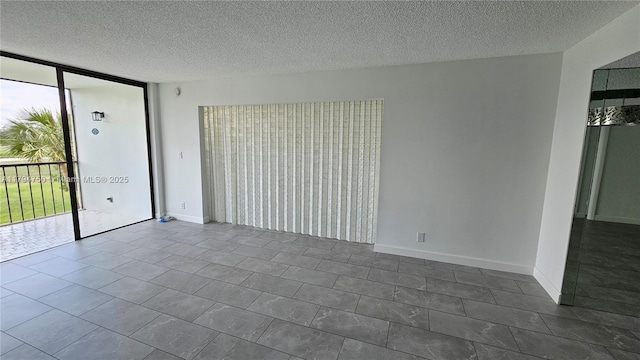 empty room featuring dark tile patterned floors, a textured ceiling, and floor to ceiling windows
