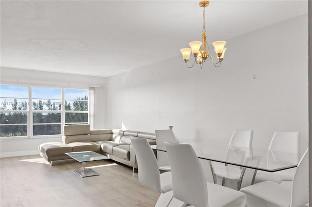 dining area with baseboards, wood finished floors, and a chandelier