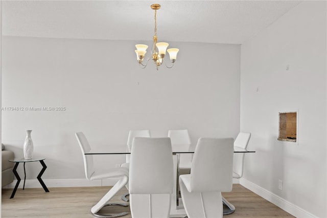 dining room with an inviting chandelier, a textured ceiling, baseboards, and wood finished floors