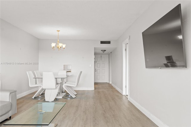 dining room featuring an inviting chandelier, baseboards, wood finished floors, and visible vents