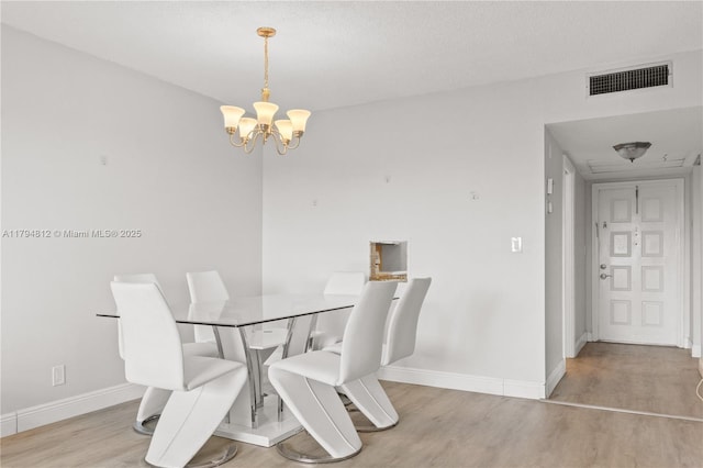 dining space with baseboards, visible vents, wood finished floors, and a chandelier