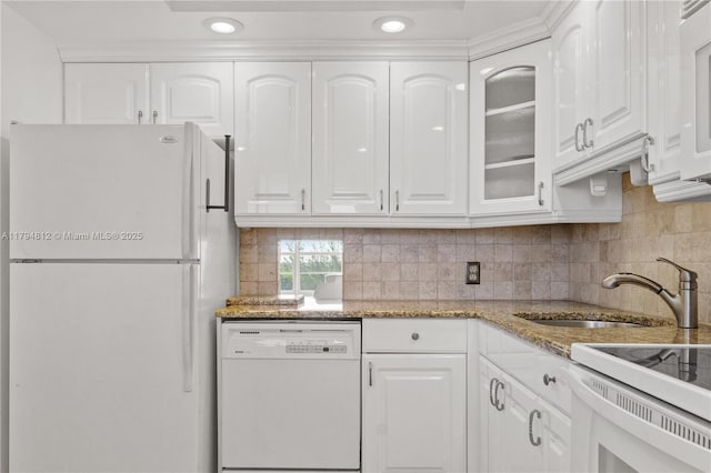 kitchen with white appliances, light stone countertops, white cabinets, tasteful backsplash, and a sink