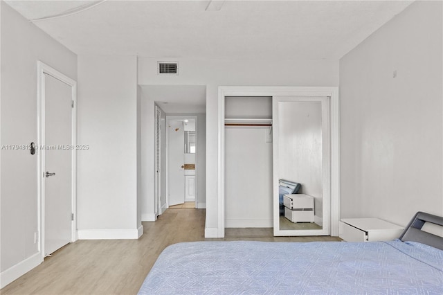 bedroom with visible vents, baseboards, wood finished floors, and a closet