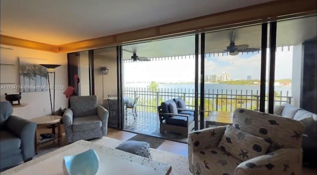 living area with a water view, a ceiling fan, and wood finished floors