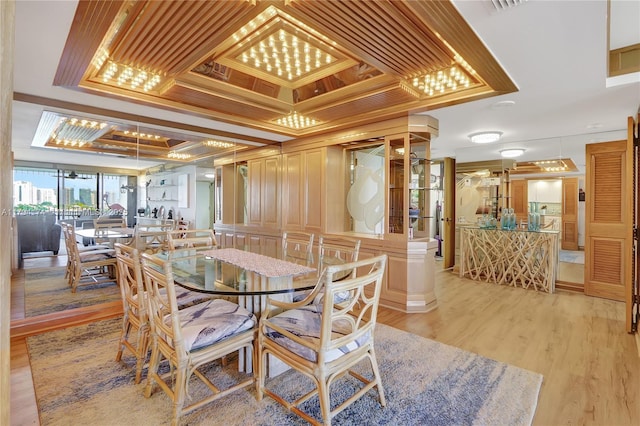 dining room with a raised ceiling and light wood-style flooring