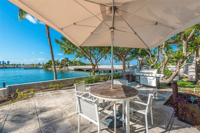 view of patio / terrace with outdoor dining area, a water view, and a grill