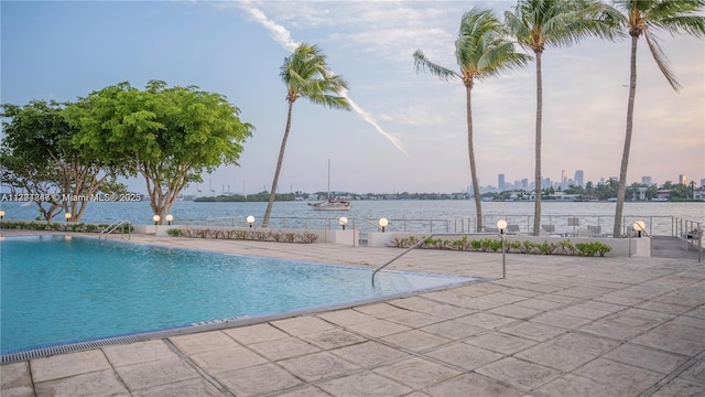 pool featuring a water view and a patio area