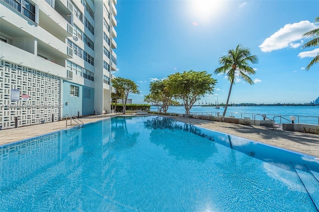 community pool with a water view and fence