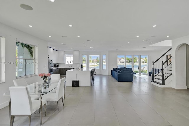 dining area featuring recessed lighting, baseboards, a water view, and stairway