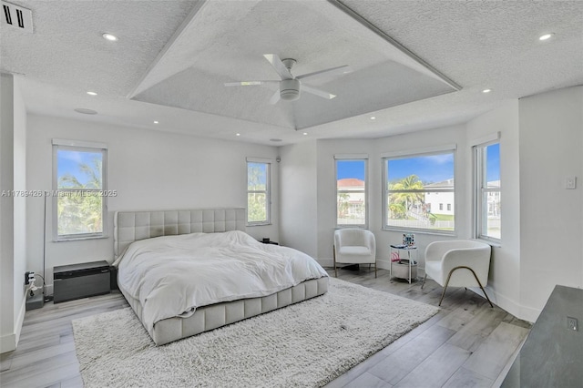bedroom with visible vents, recessed lighting, a textured ceiling, a tray ceiling, and a ceiling fan