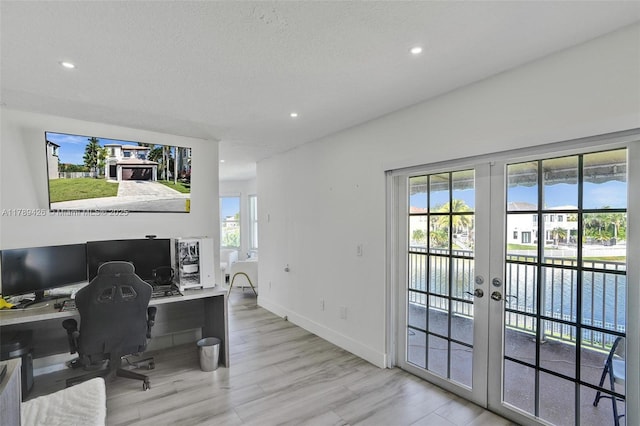 office space featuring recessed lighting, baseboards, a water view, and wood finished floors