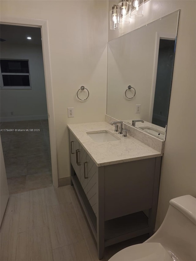 bathroom with toilet, baseboards, and vanity