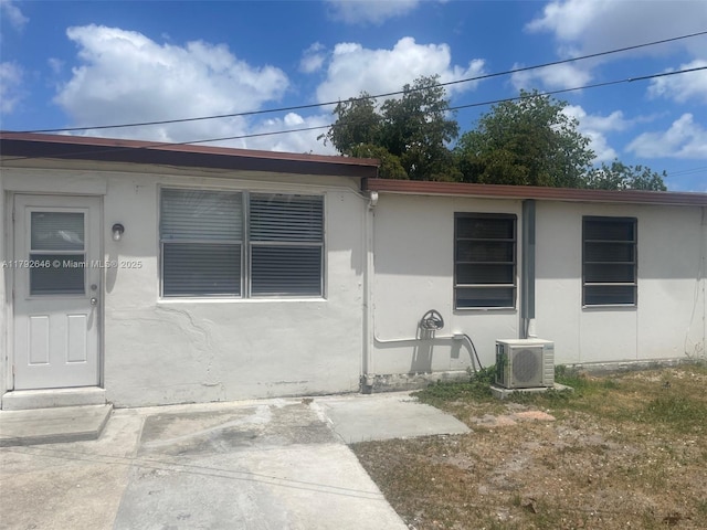 view of exterior entry featuring ac unit and stucco siding