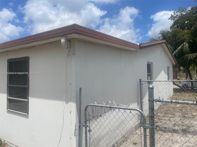 view of side of home with fence and stucco siding