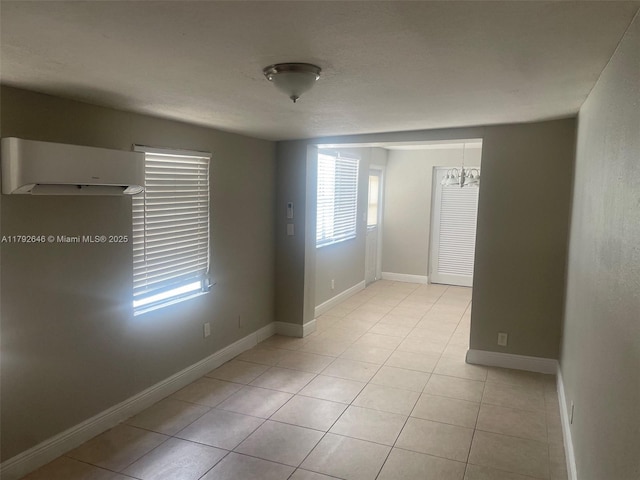 unfurnished room with light tile patterned flooring, baseboards, and a notable chandelier