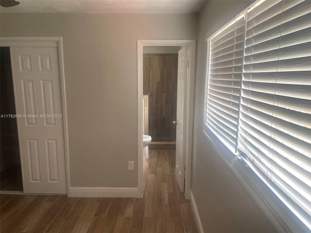 hall with baseboards and wood finished floors