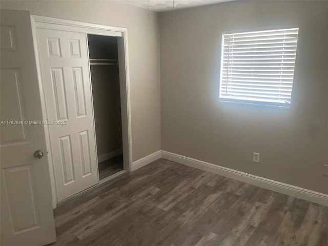 unfurnished bedroom featuring dark wood-type flooring, baseboards, and a closet