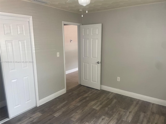 unfurnished bedroom featuring baseboards, ornamental molding, and dark wood-style flooring