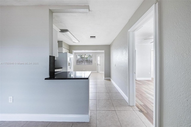 6808 SW 22nd Ct, Miramar, FL 33023 - kitchen with white refrigerator with ice dispenser, light tile patterned floors, a peninsula, baseboards, and white cabinets