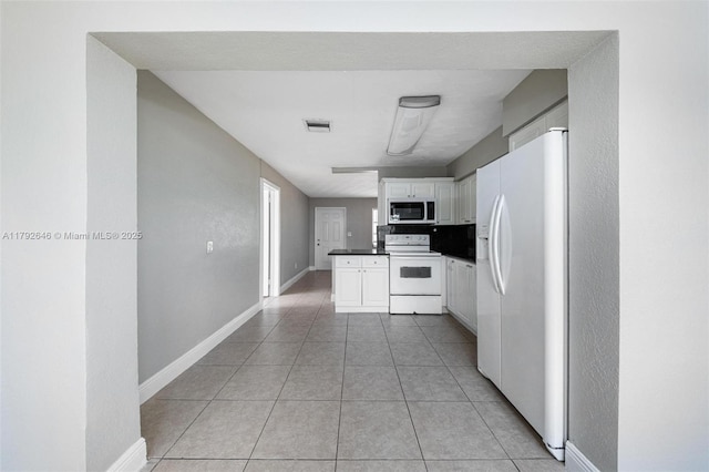 6808 SW 22nd Ct, Miramar, FL 33023 - kitchen featuring white appliances, dark countertops, light tile patterned flooring, white cabinets, and baseboards