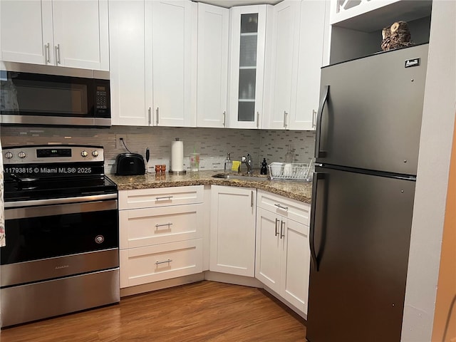 kitchen featuring decorative backsplash, stainless steel appliances, white cabinetry, and a sink