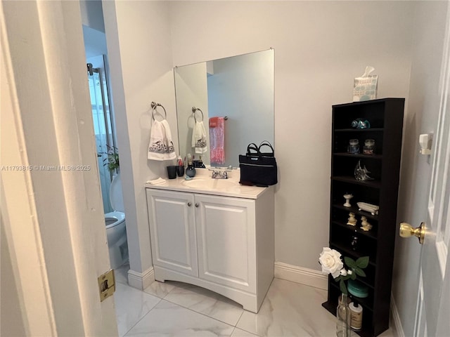 bathroom with vanity, baseboards, toilet, and marble finish floor