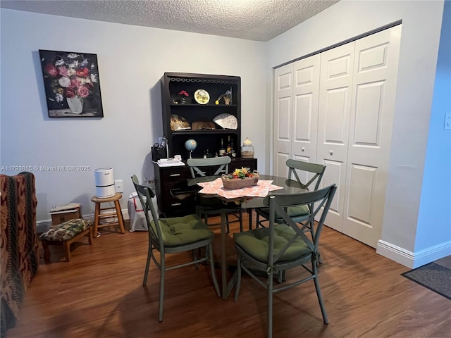 dining space featuring baseboards, a textured ceiling, and wood finished floors