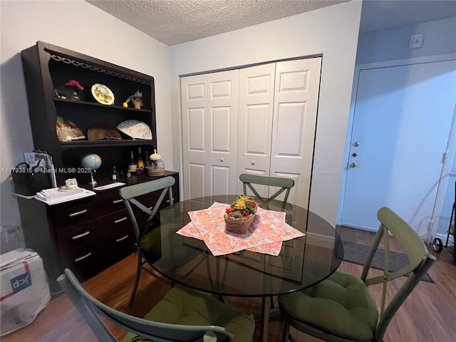 dining room with dark wood-style flooring and a textured ceiling
