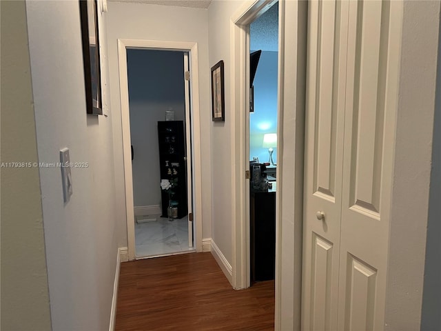 hallway with baseboards and dark wood-type flooring