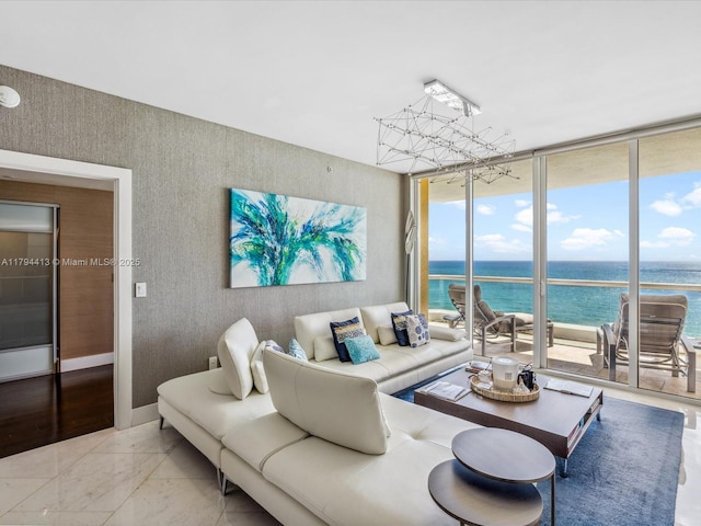 living room with a water view, floor to ceiling windows, an inviting chandelier, and marble finish floor