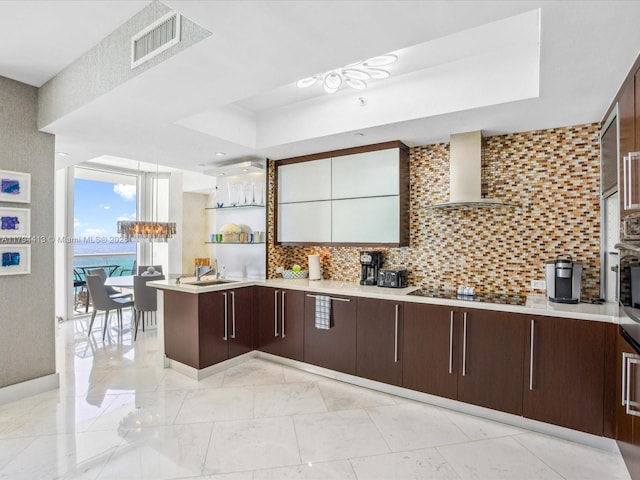 kitchen featuring wall chimney range hood, visible vents, black electric cooktop, dark brown cabinets, and a tray ceiling