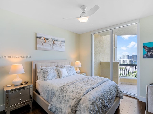 bedroom with a city view, ceiling fan, dark wood-type flooring, and access to exterior