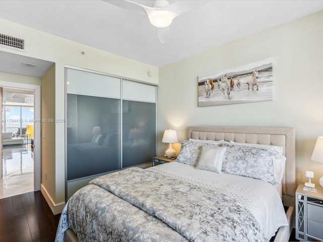 bedroom featuring ceiling fan, dark wood-style flooring, visible vents, baseboards, and a closet