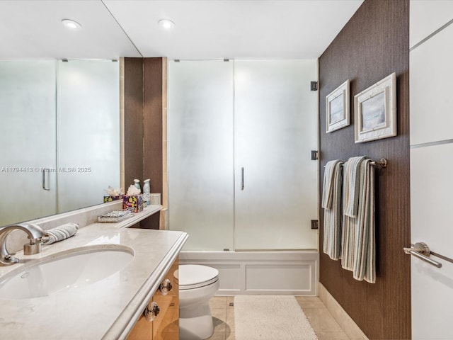full bathroom featuring vanity, tile patterned floors, combined bath / shower with glass door, toilet, and a decorative wall