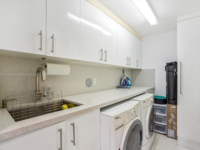 washroom with a sink, cabinet space, and independent washer and dryer