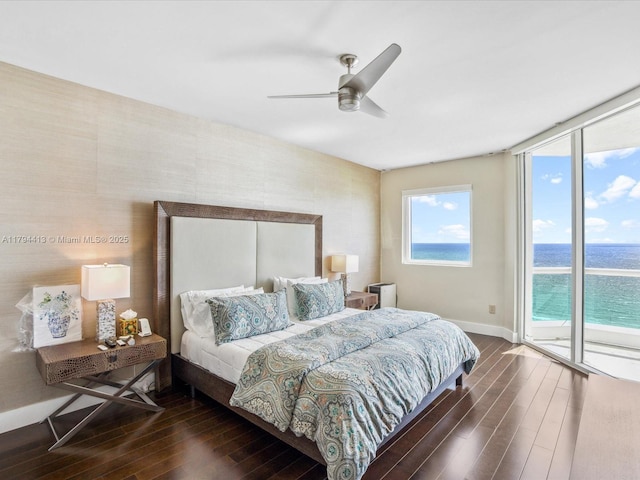 bedroom featuring access to exterior, a ceiling fan, baseboards, a water view, and dark wood-style floors