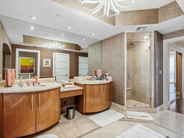 bathroom featuring an inviting chandelier, tile patterned flooring, visible vents, a shower stall, and a sink