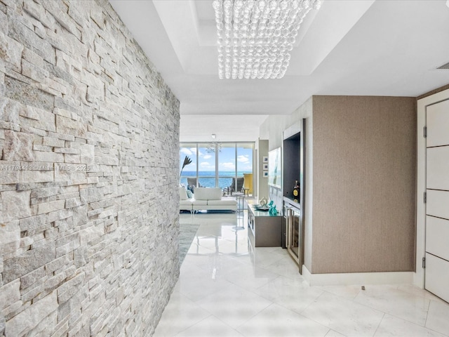 corridor with an inviting chandelier and a tray ceiling